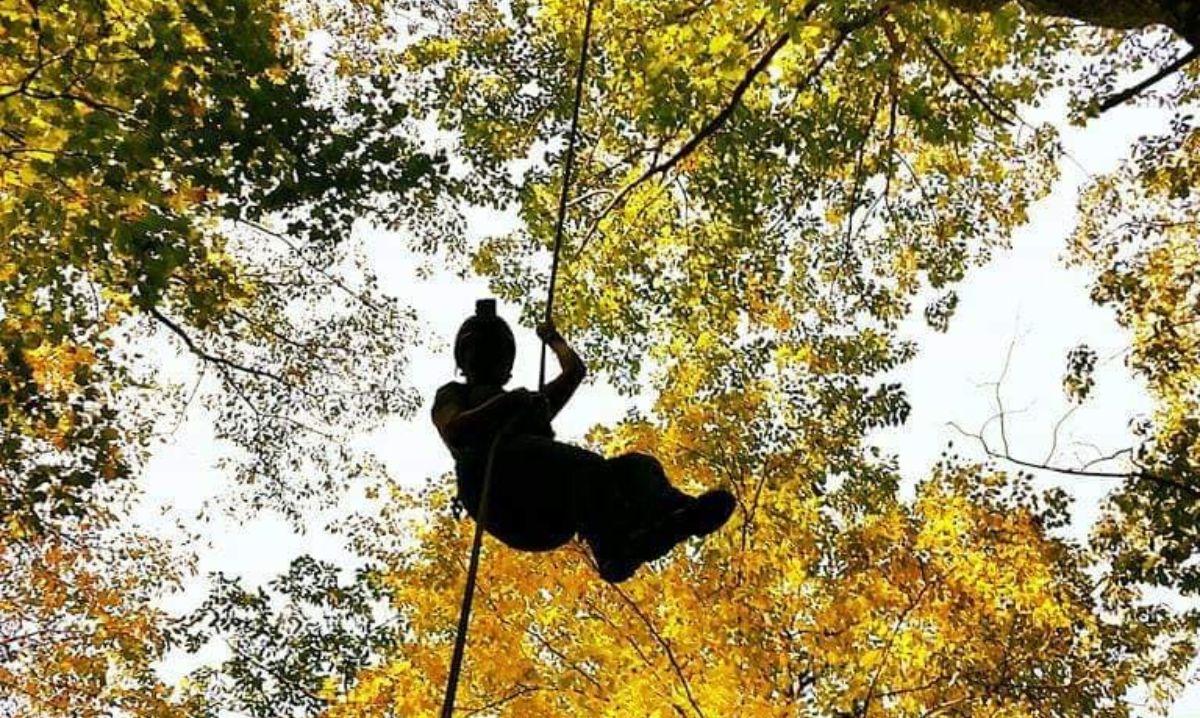 A silhouette of a person ziplining through the colorful autumn canopy at Hocking Hills, Ohio, offering a thrilling outdoor adventure surrounded by vibrant fall foliage.