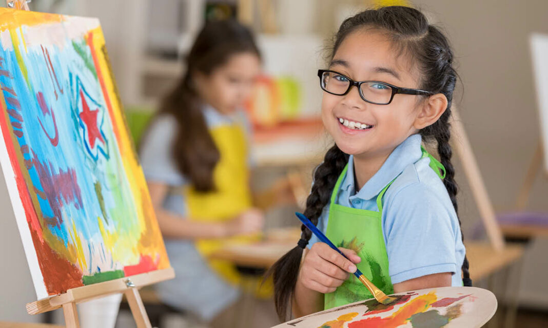 Joyful girl art student paints in a studio