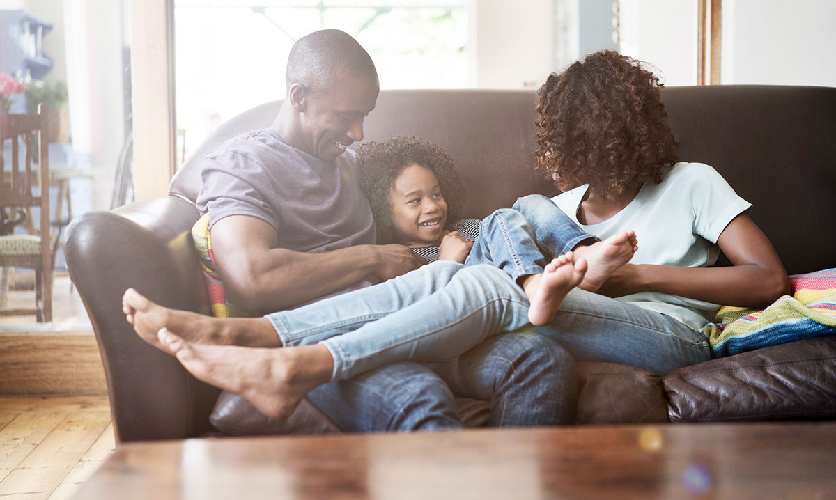 Family of three laughing on a couch
