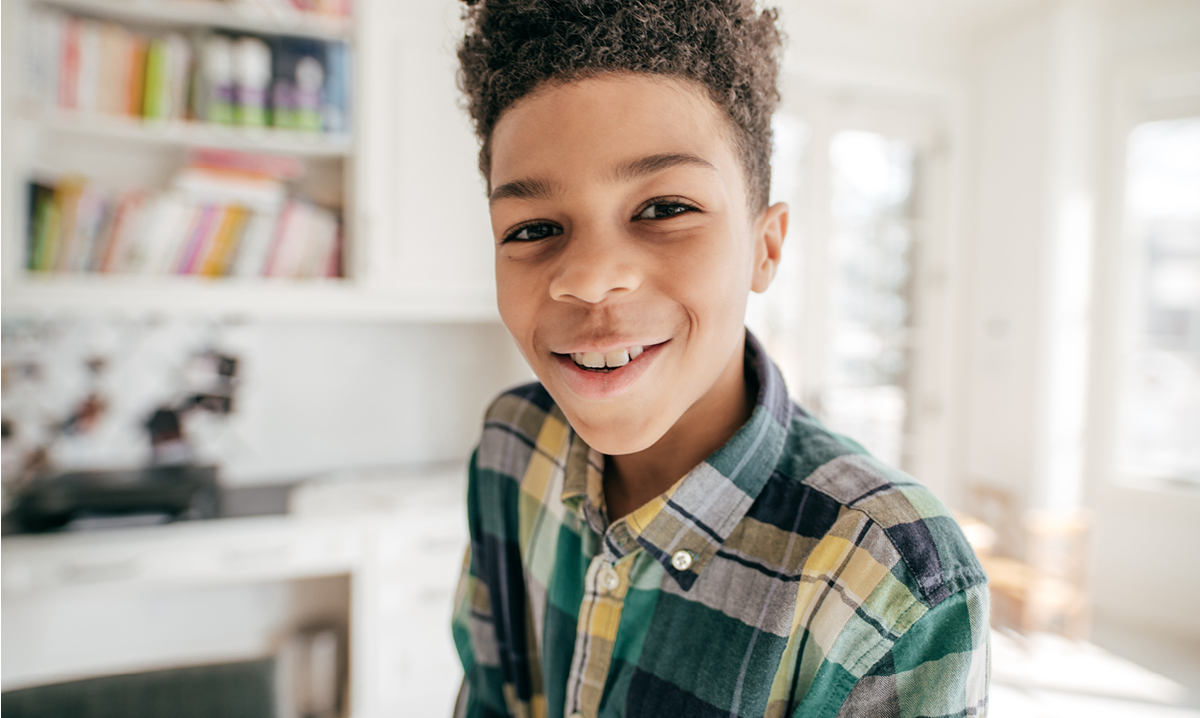 Little boy smiles from inside a house