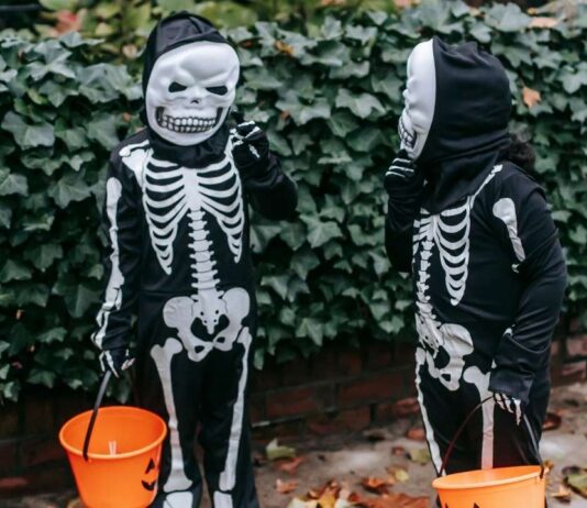 Southfield Police Trunk or Treat Two kids dressed in skeleton costumes hold orange buckets while trick-or-treating during a family-friendly Halloween event outdoors.