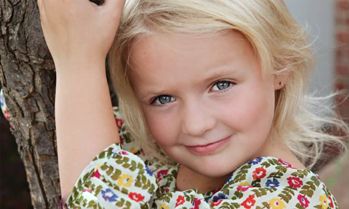 Little blond girl hugging tree