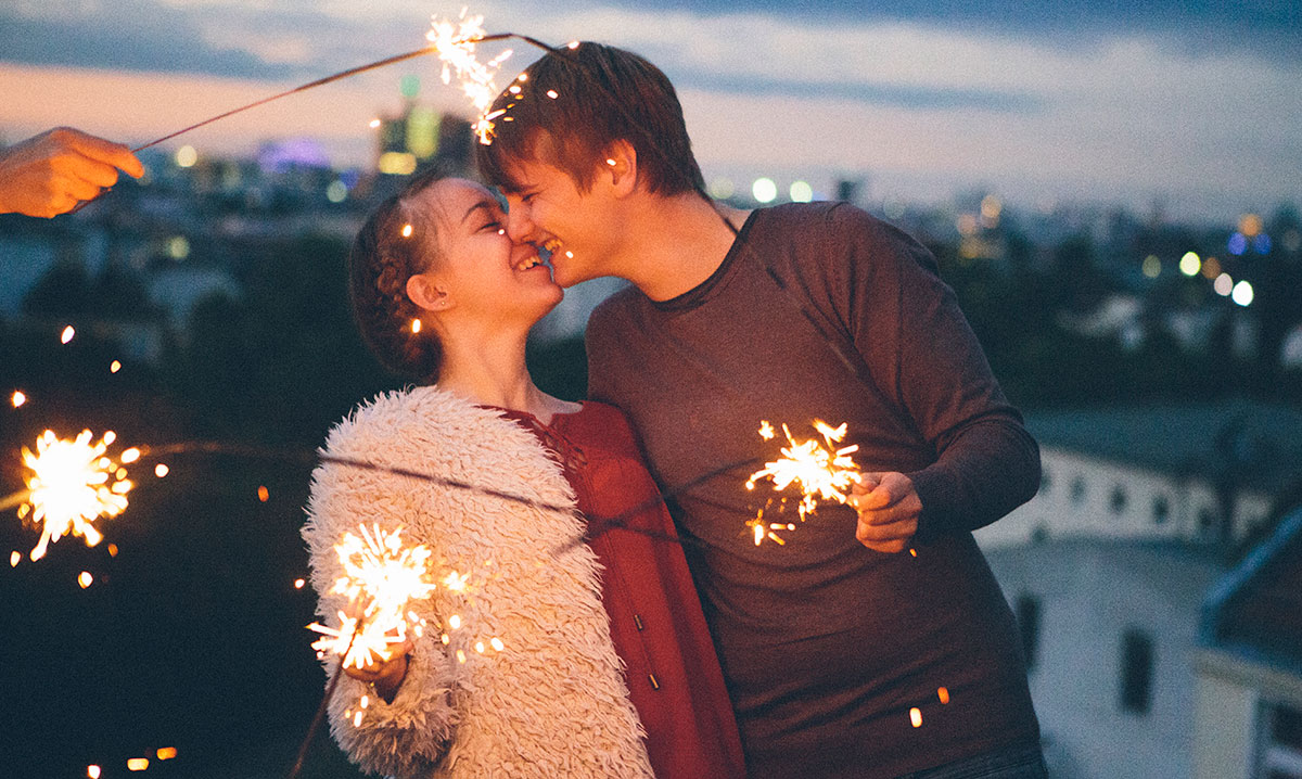 Two teenagers sharing a joyful, intimate moment while holding sparklers, reflecting a positive, open conversation about teen relationships and sexual activity.