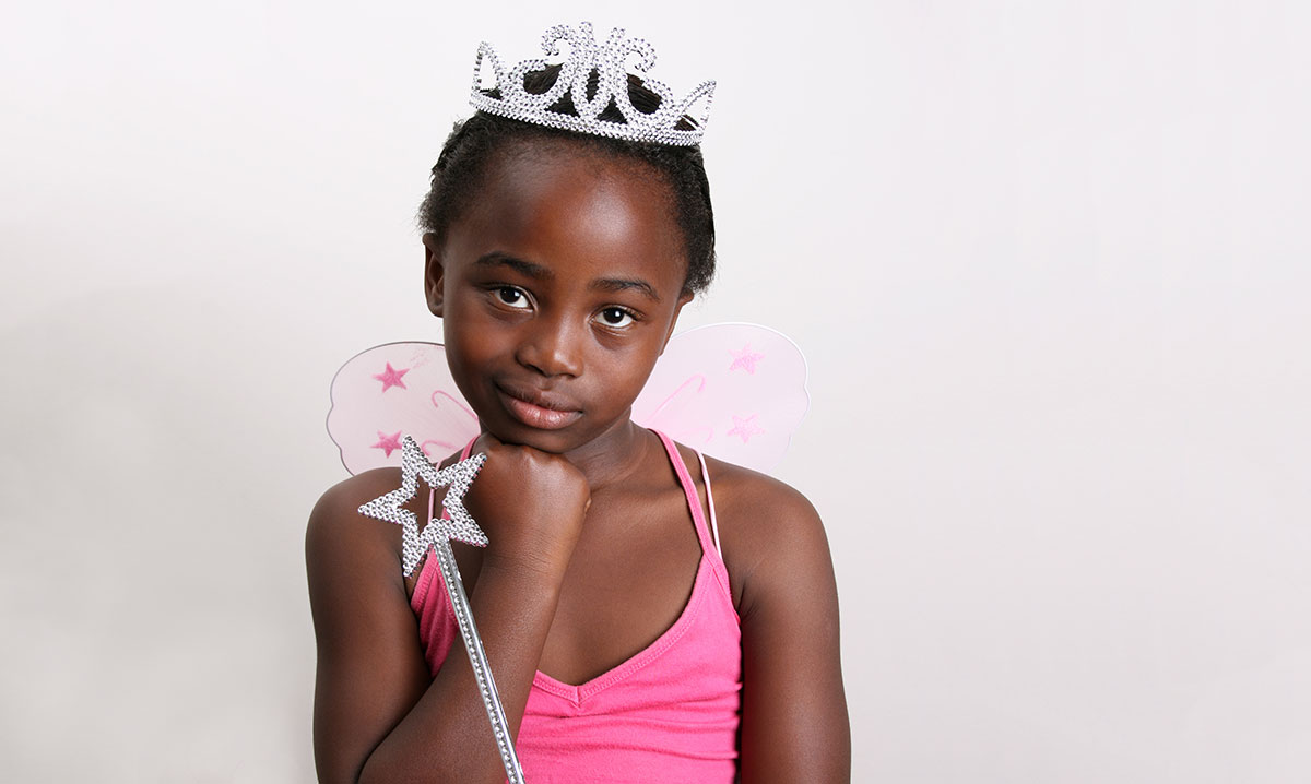 A little girl in a pink princess costume on a white background