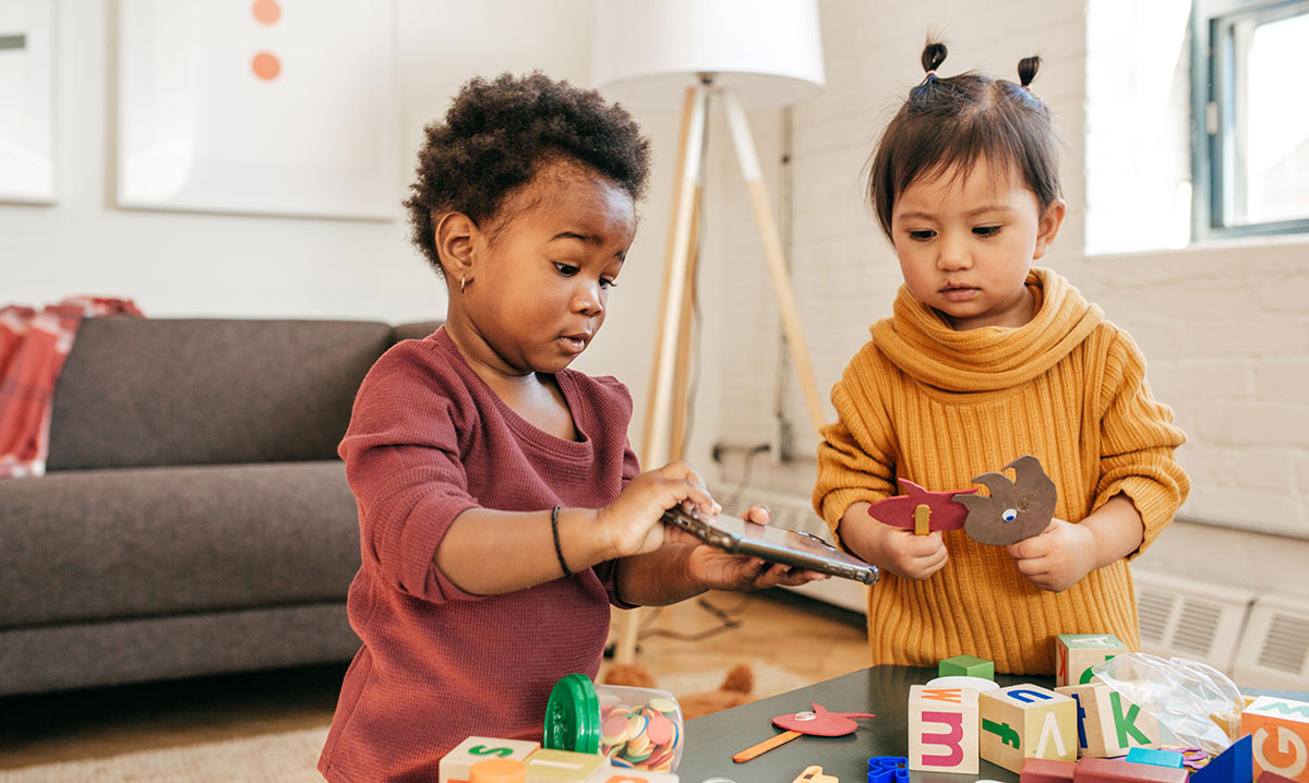 Two toddlers playing with blocks together