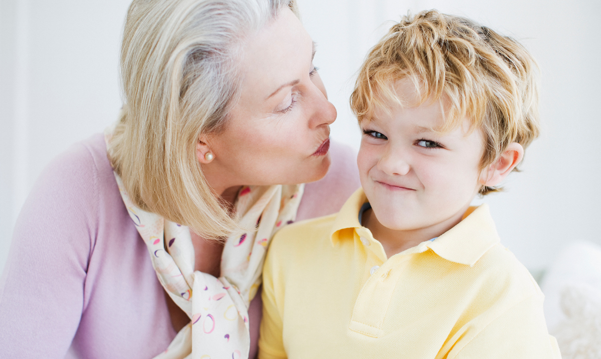 Child pulling away from woman giving kiss