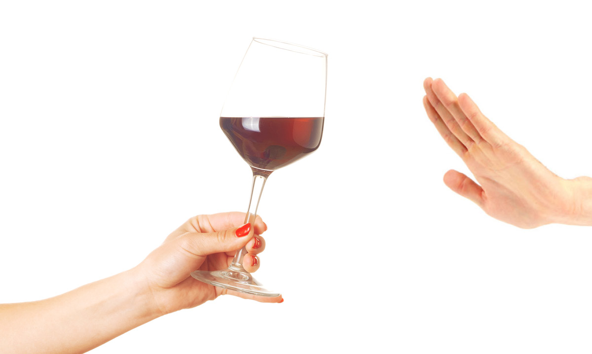 Hand waving away a glass of wine on a white background