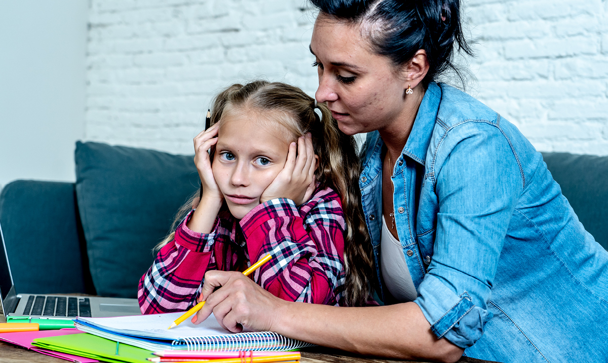 Little girl looks frustrated as her mom helps her with her homework