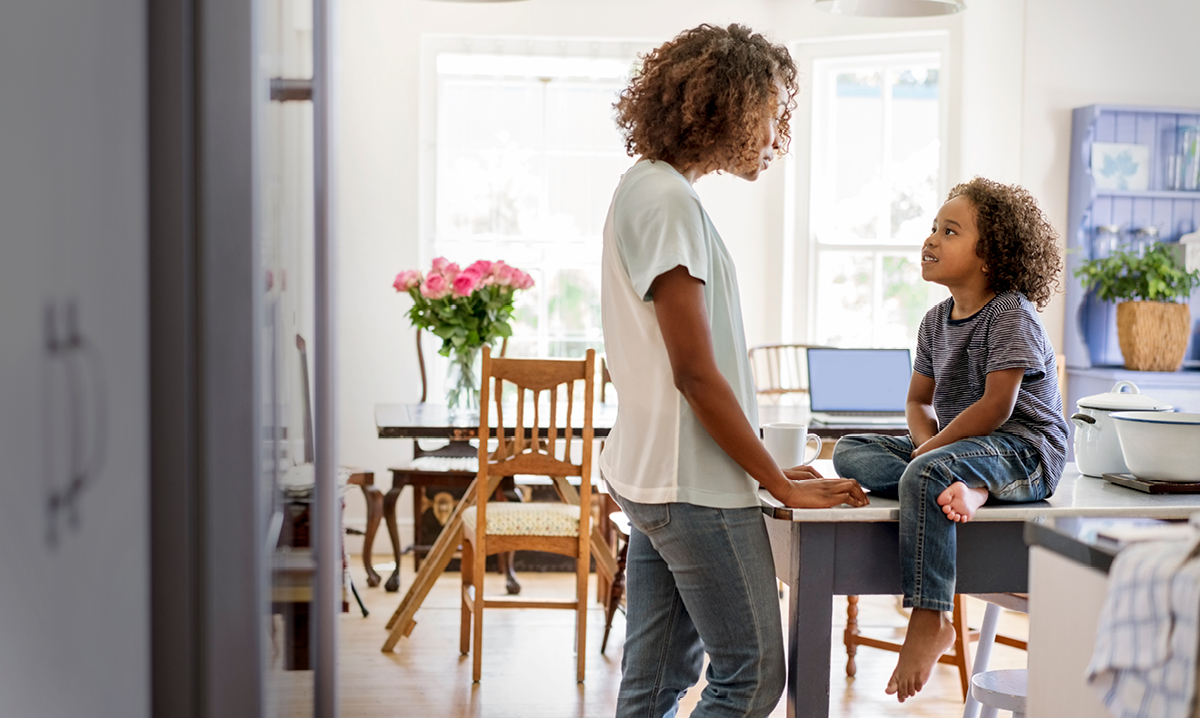Grown women talking to a little girl as she sits on a desk