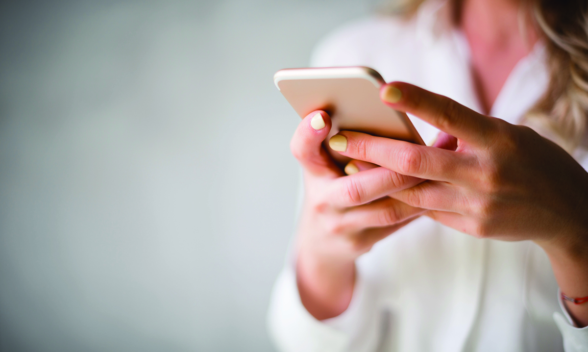 A woman in a white shirt holding an phone