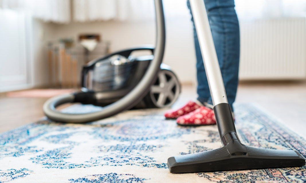Woman in socks using a vacuum cleaner on the rug