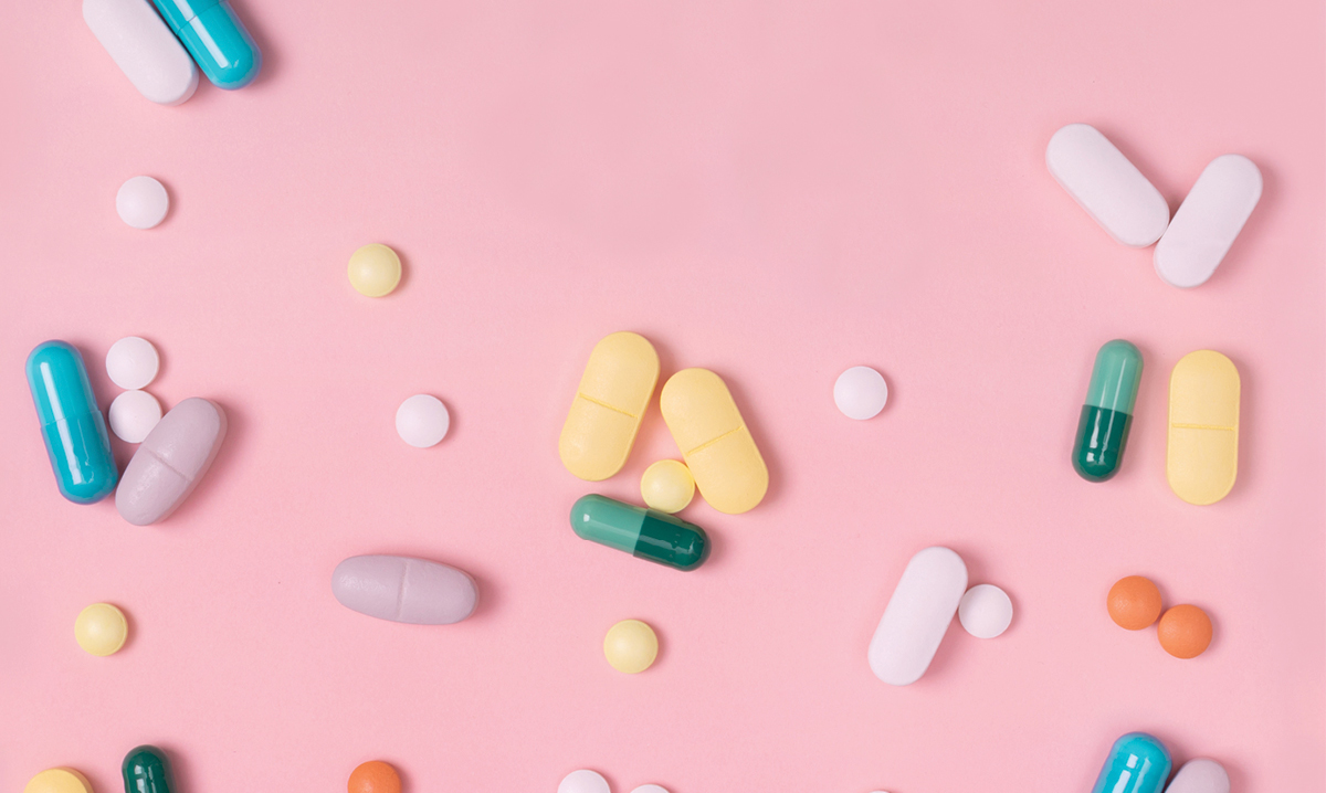 Different colored pills on a pink background