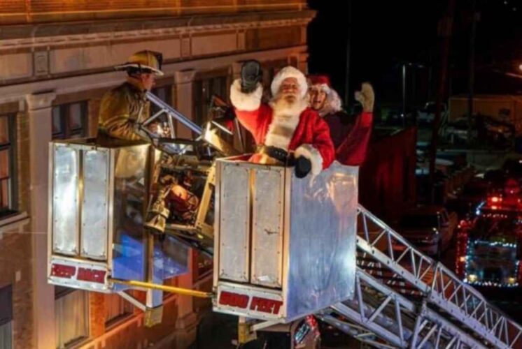 Santa waves from a firetruck lift during the Holly Dickens Festival lighted parade creating a festive holiday moment for families