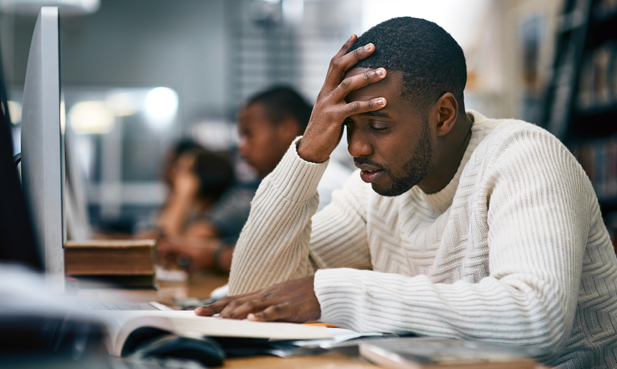 Man hold his head while reading a book