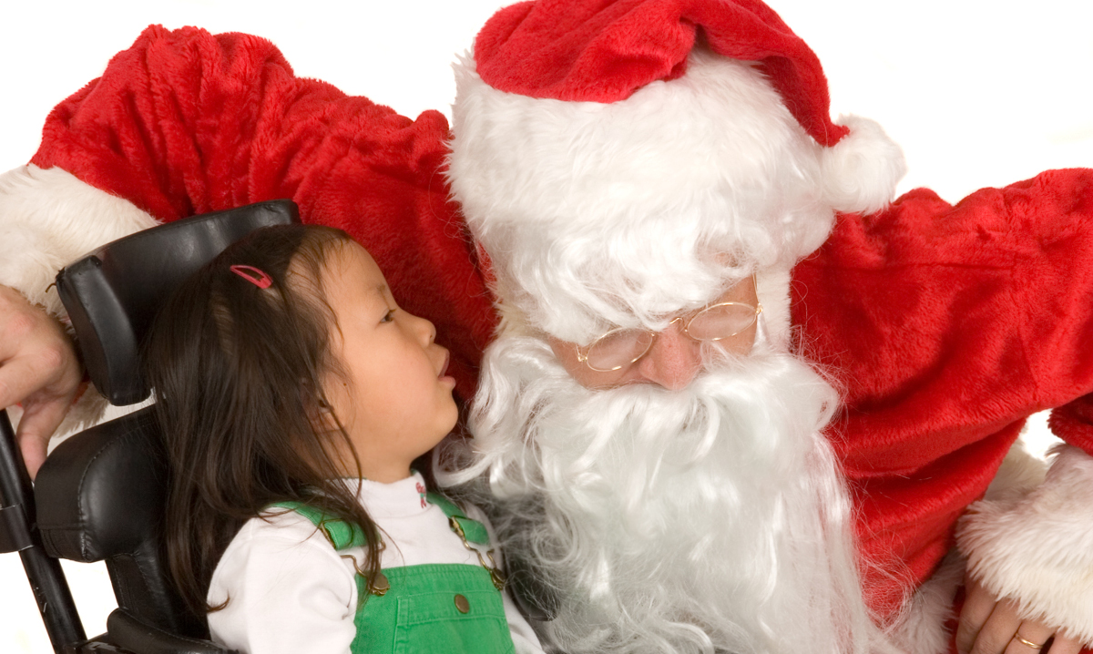 Girl in wheelchair whispering to Santa