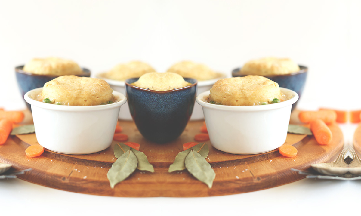 Vegan pot pies on a wooden cutting board on a white background