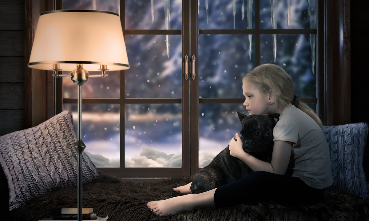 Girl holding her knees in front of a window