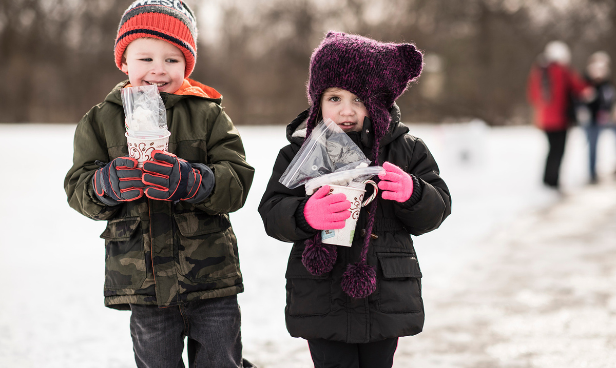 Two kids in warm clothes carrying goodies