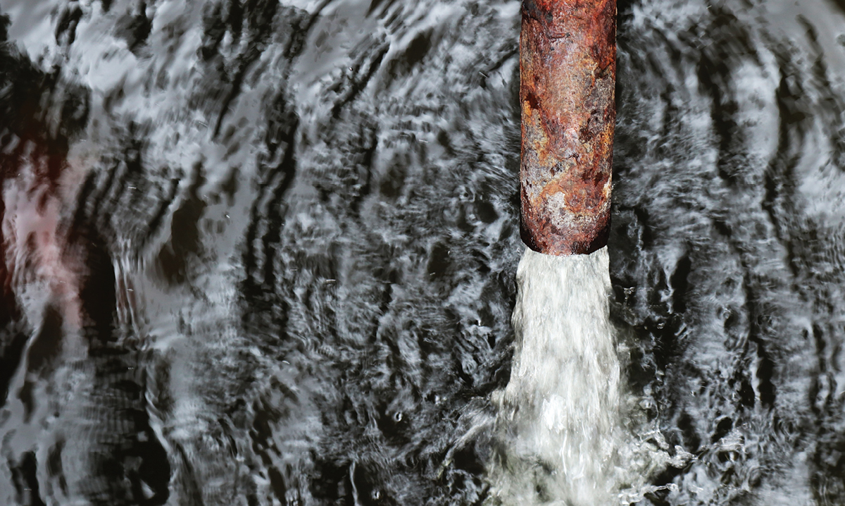 A rusty pipe pumping water into a larger body of water
