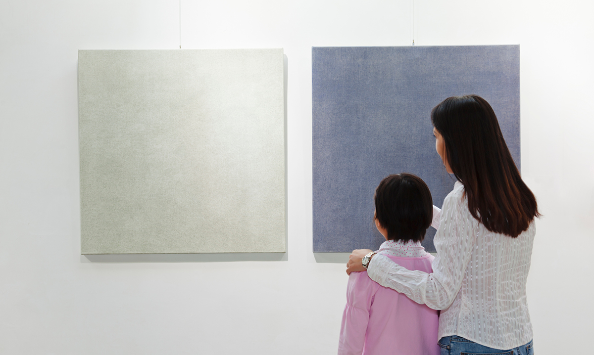 Woman and child staring at two pieces of art on a wall