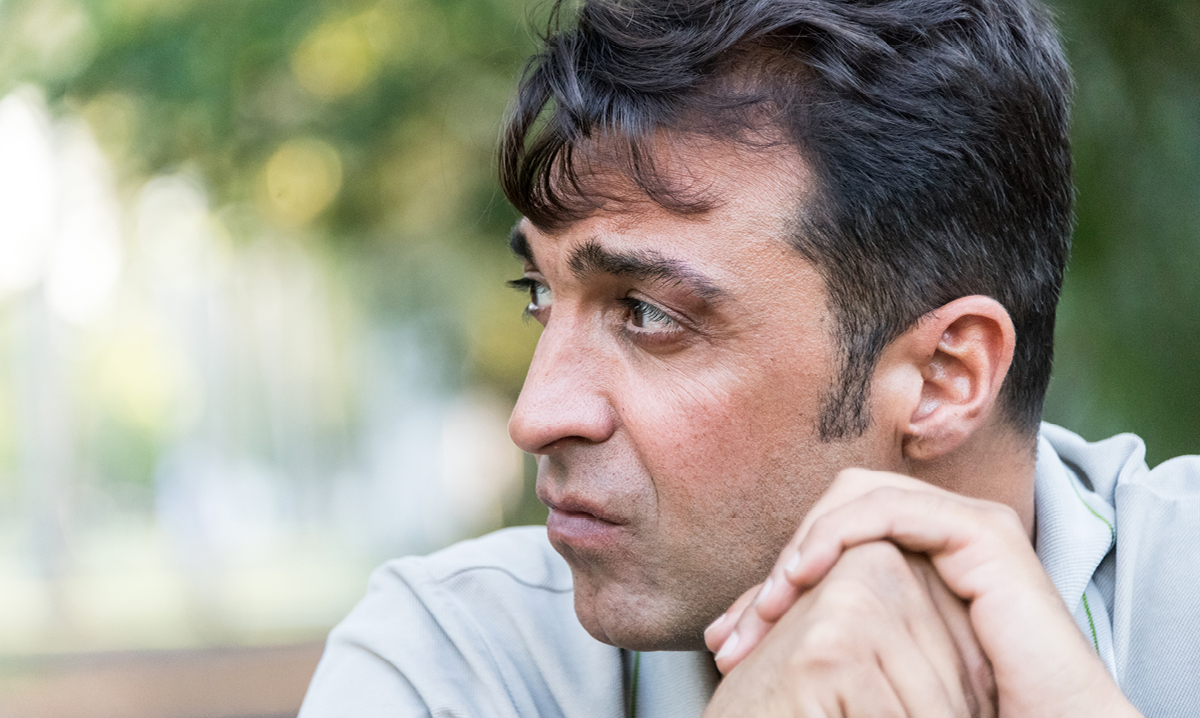 A worried middle aged man sitting on a park bench