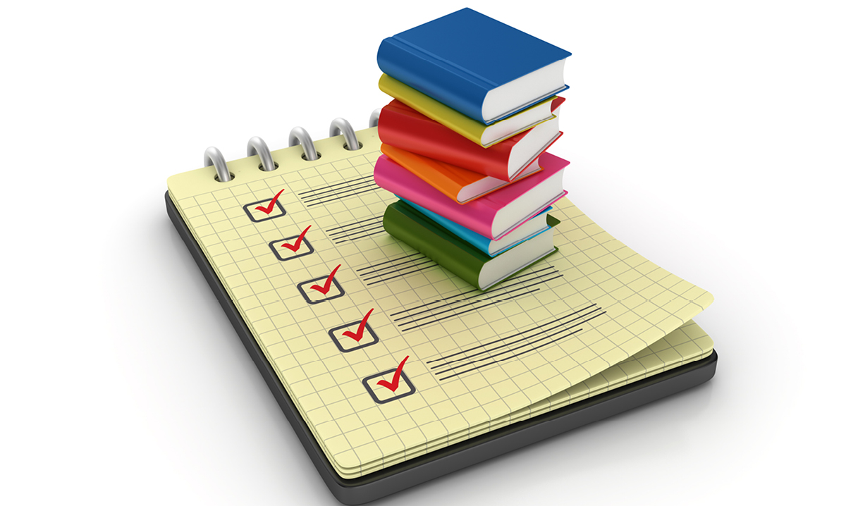 Checklist on a yellow pad of paper with small books stacked on it