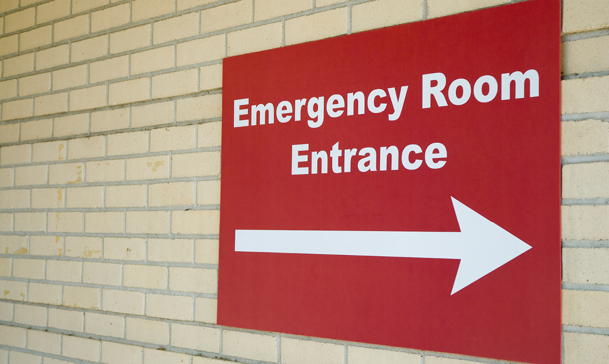 Red emergency room entrance sign on a beige brick wall