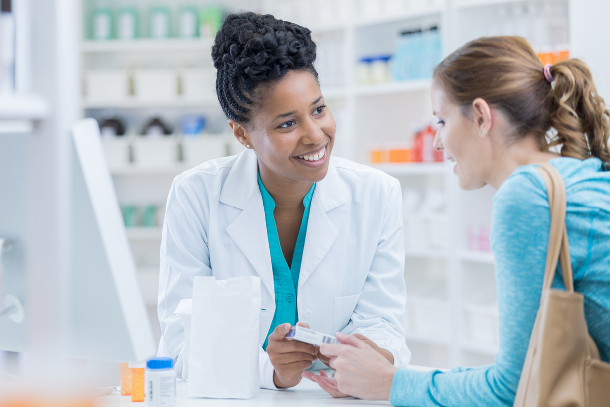 A pharmacist offers advice to a woman with a purse