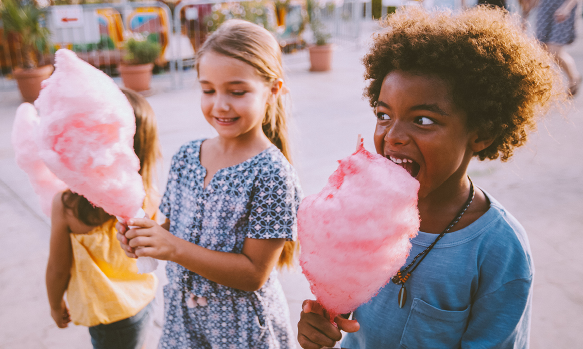 Two girls eating pink cotton candy at a fair