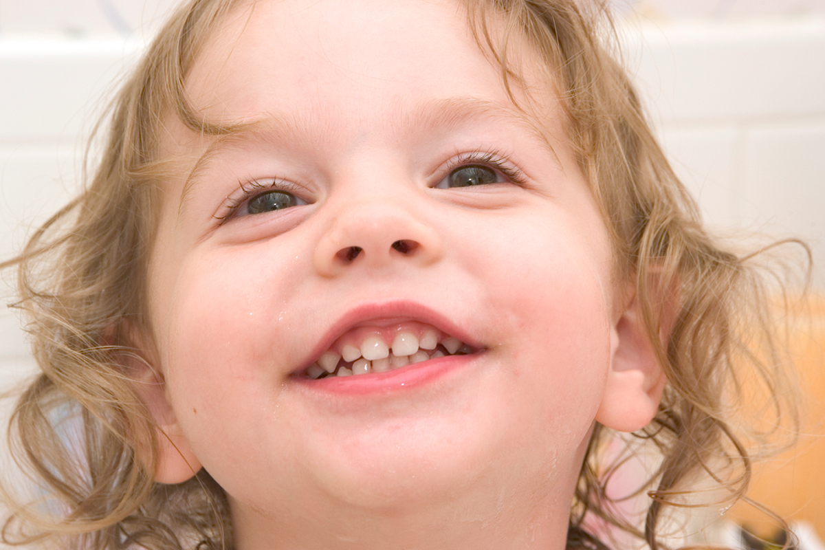 A little girl tilts up her head to show her nose