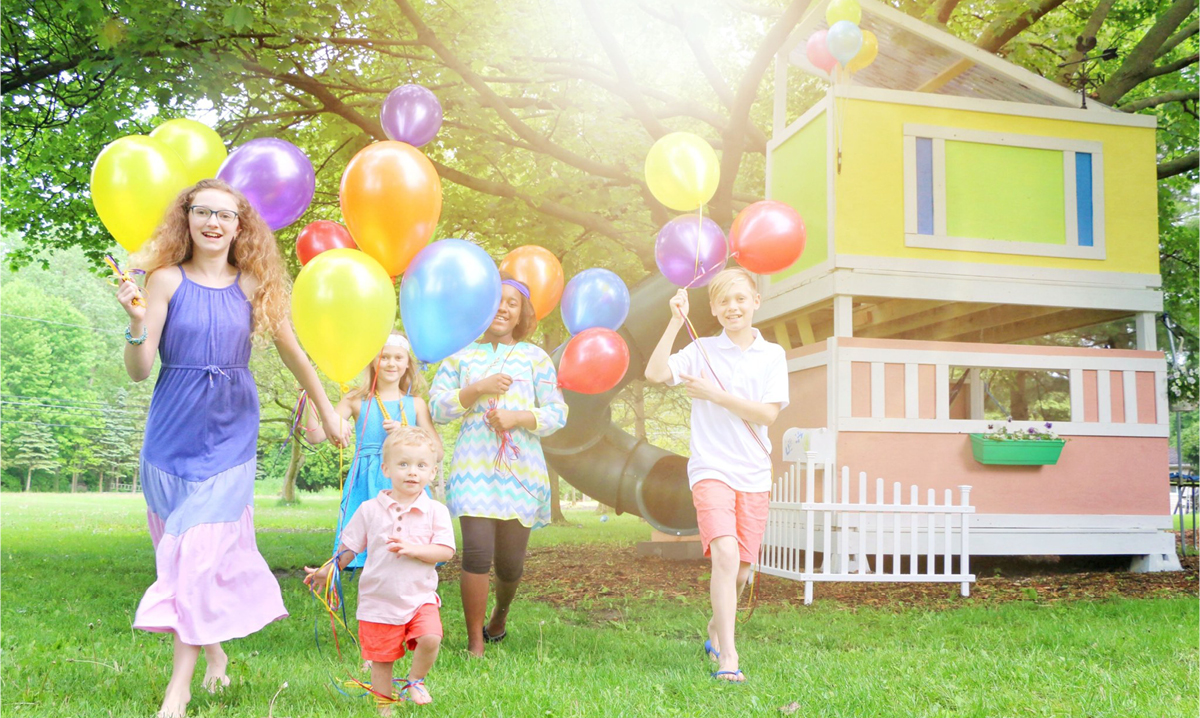 Children running with balloons in front of Up movie treehouse in Livonia, Michigan
