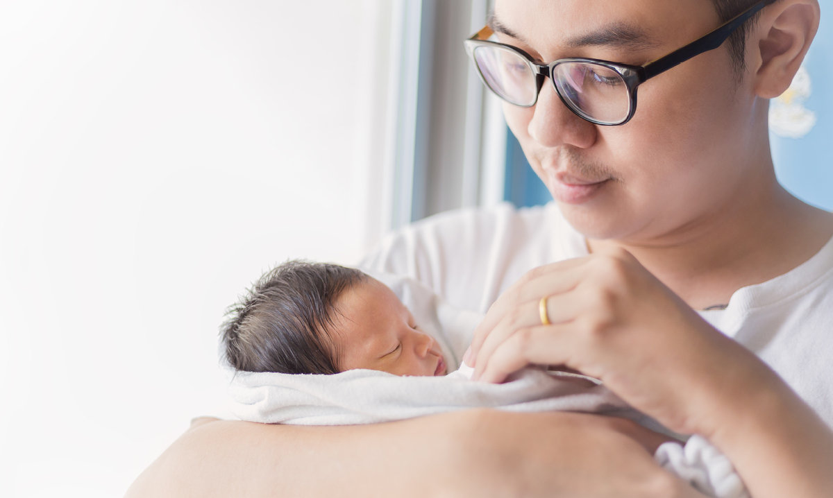Young dad with glasses holding baby