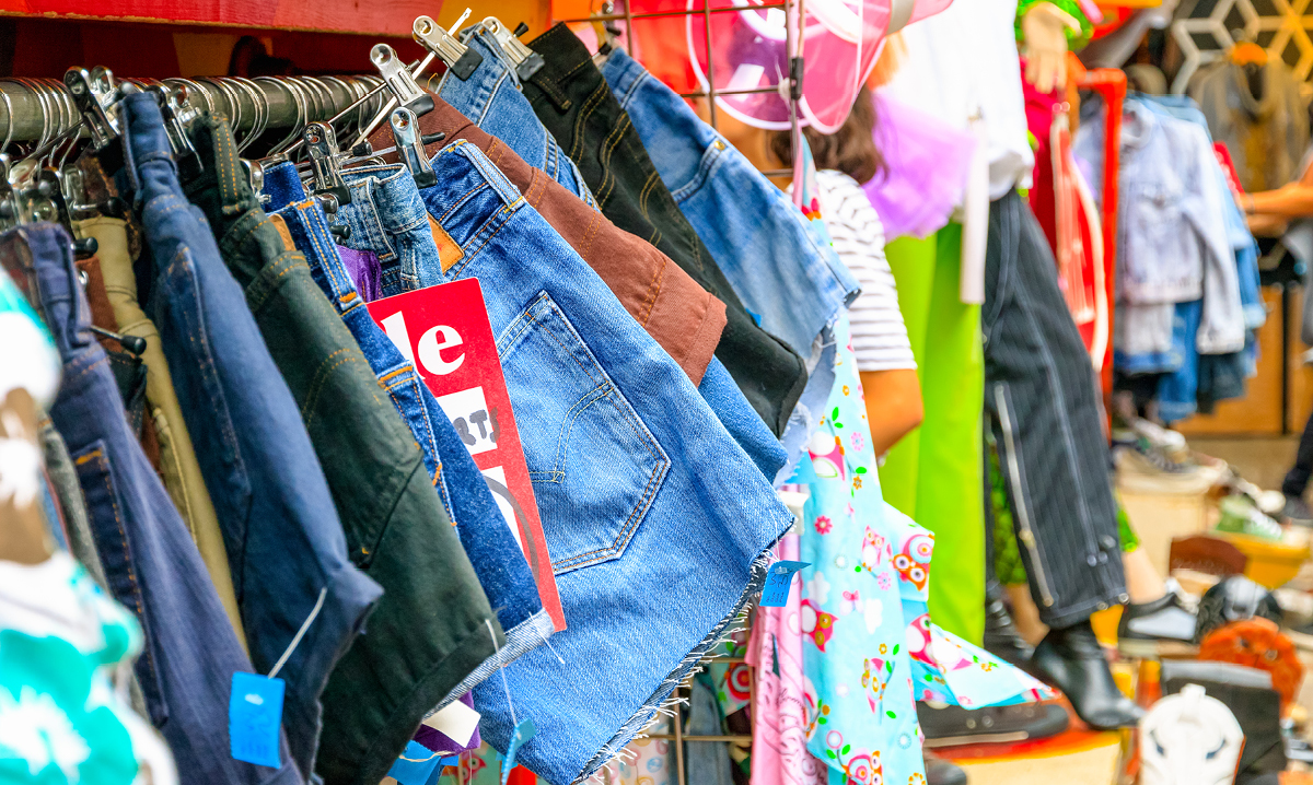 clothing hanging up at a garage sale with other trinkets for sale in the background
