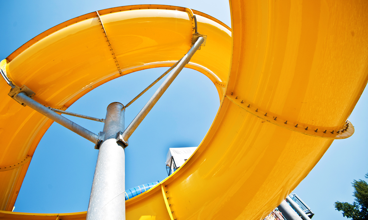 A yellow winding water slide against a blue sky