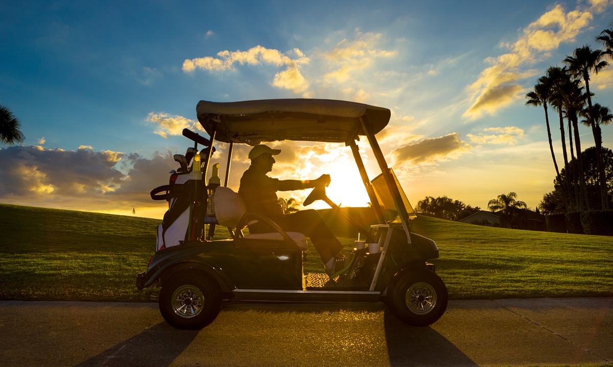 Senior man driving a golf cart in a tropic location
