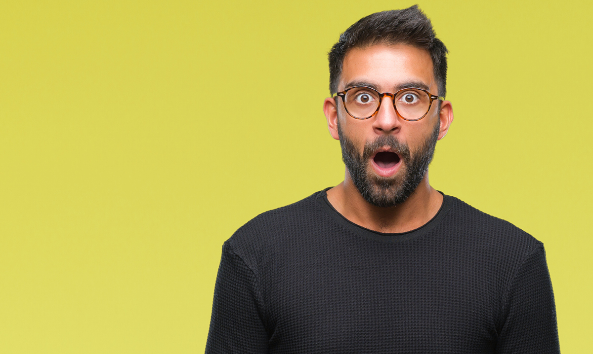 A dumbfounded young man in glasses on a yellow background
