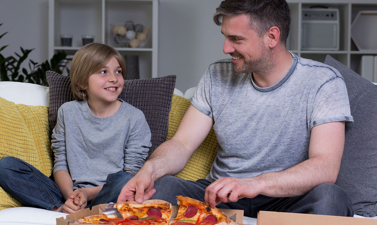 A dad shares pizza with his son