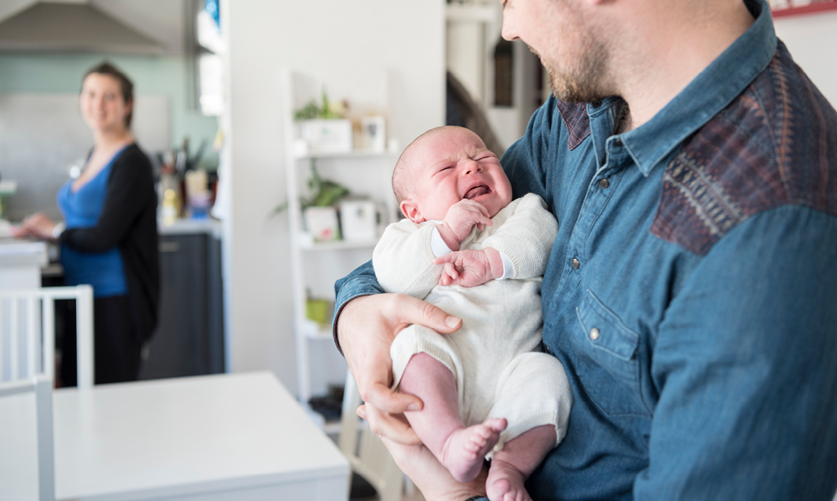 Dad rocks new baby while mom watches on