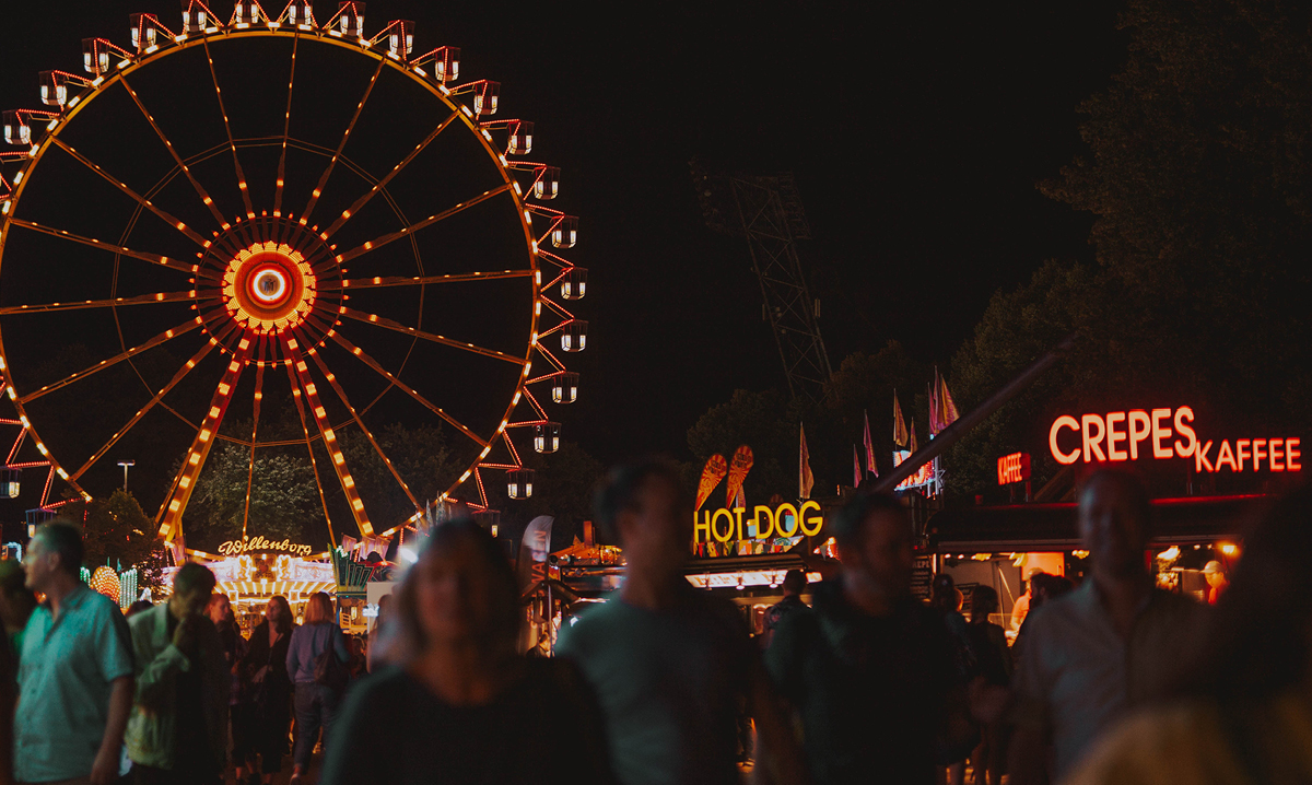 The ferris wheel at a carnival lit up against the dark sky