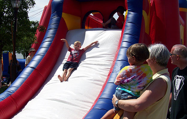 Kid sliding down inflatable slide at the Farmington Founders Festival