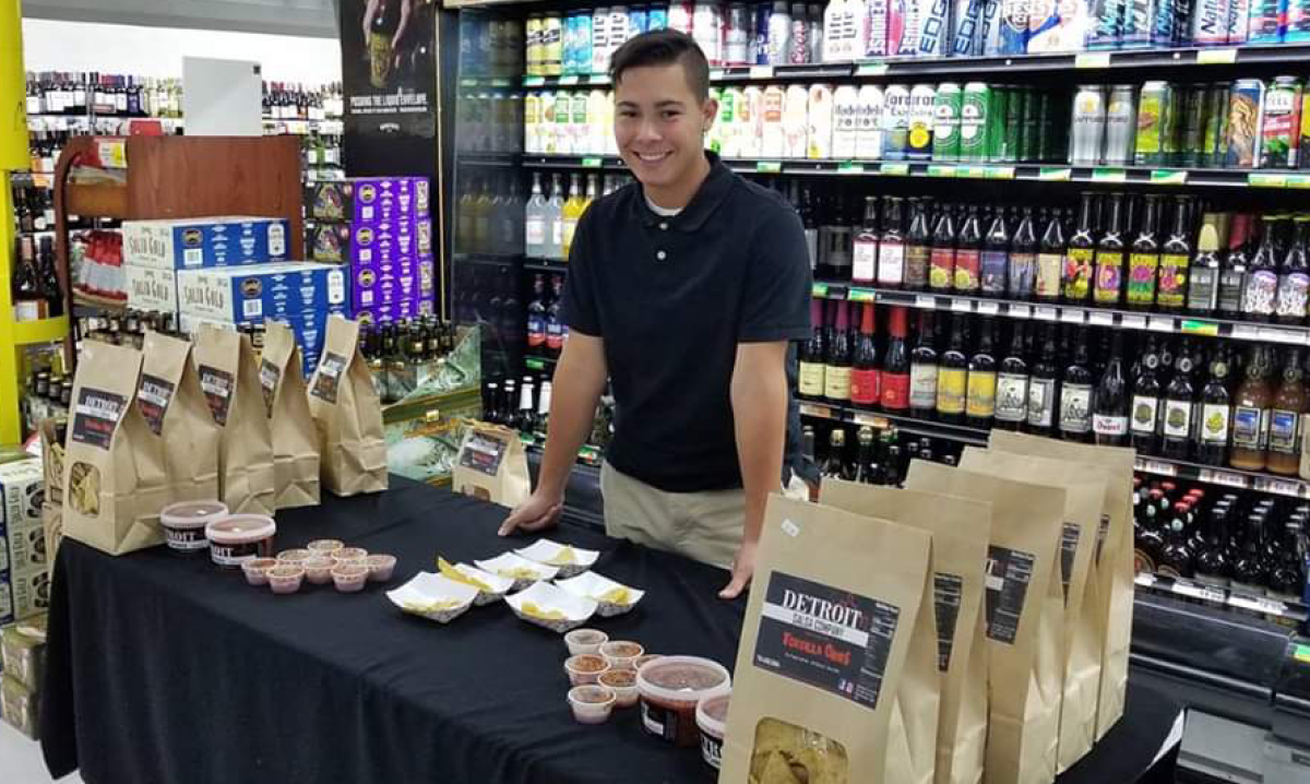 Finn Gomez standing behind a table of products from the Detroit Salsa Company