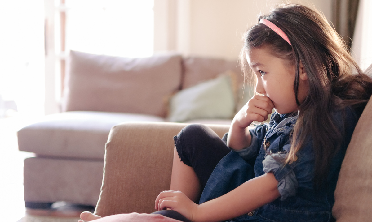 A little girl is watching TV on the couch