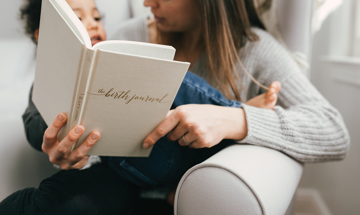 women holding baby while reading The Birth Journal