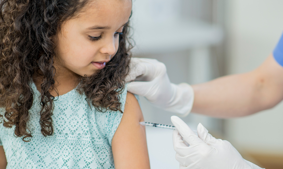 Child receiving a vaccination in her arm.