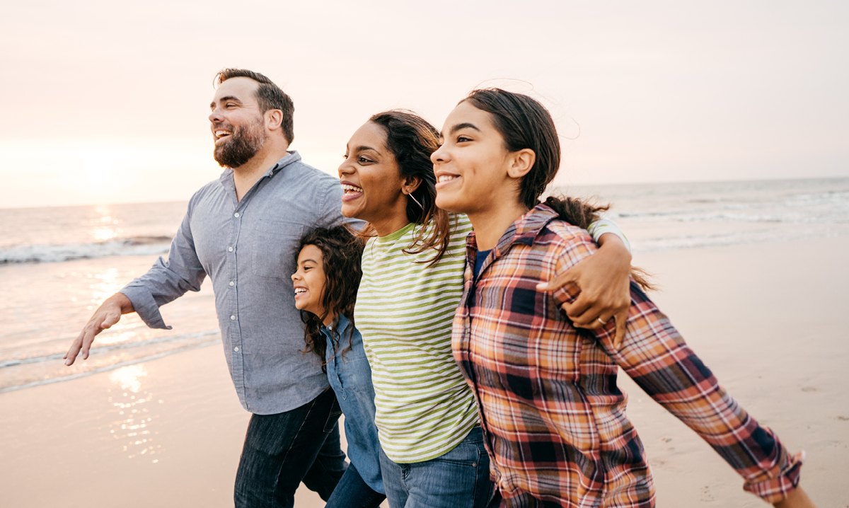 Family with two teen girls smiling on a beach