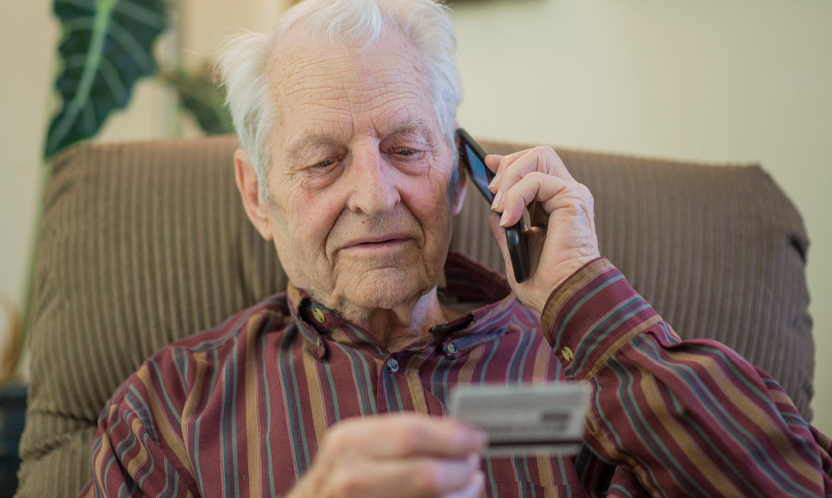 Old man on phone looking at credit card