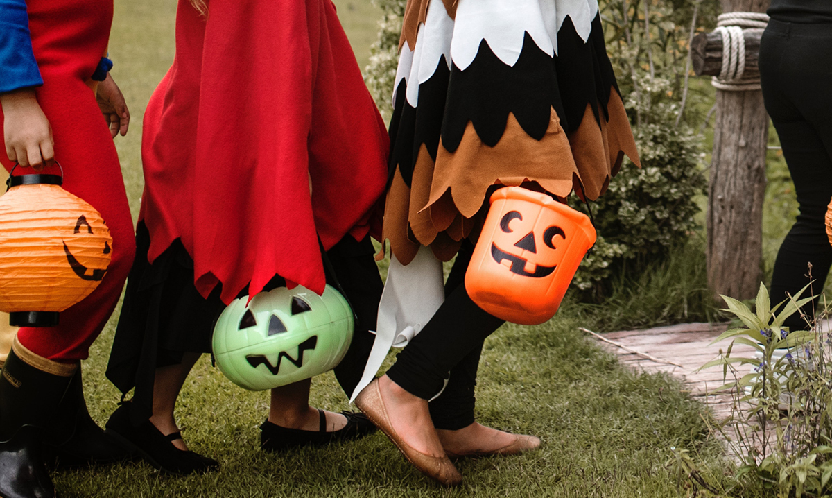 Three children in costume carrying trick-or-treating buckets