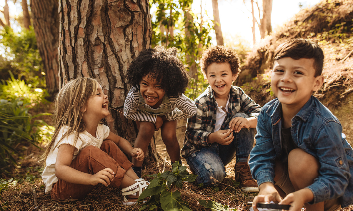 Four kids playing in front of a tree