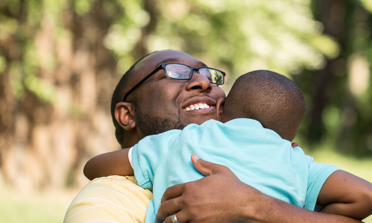 Little boy in a blue shirt hugging a man