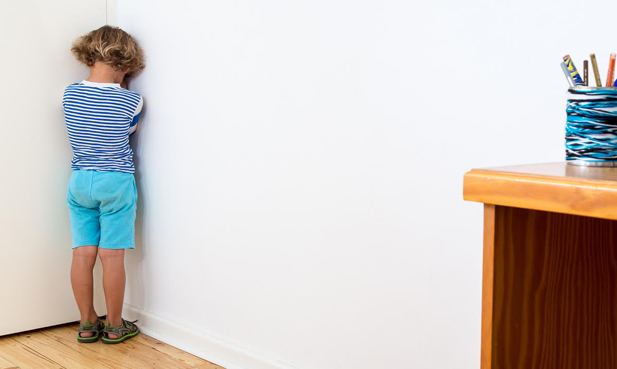 Little boy in blue standing with his face in the corner